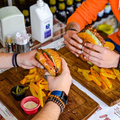 Two people eating burgers with fries at a restaurant, captured in a top view setting.
